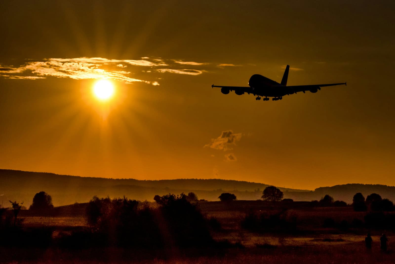 Wide-body jet silhouetted against the setting sun