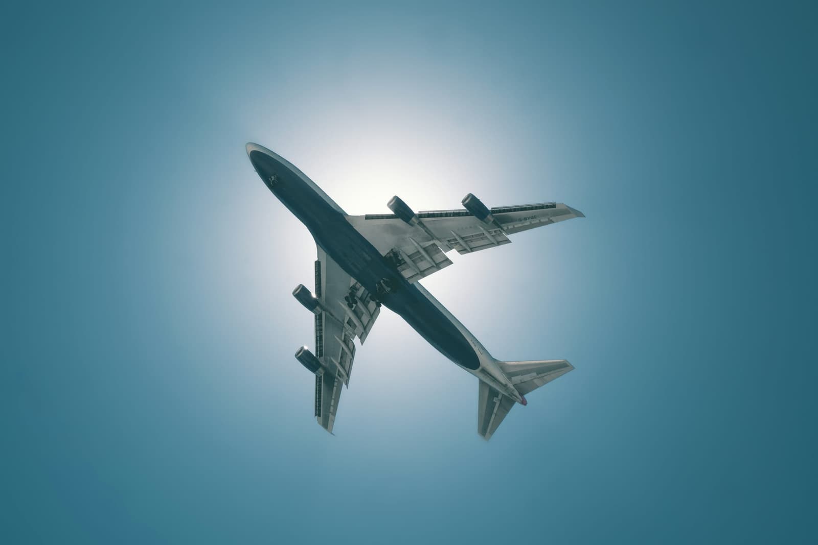 Wide-body cargo jet overhead against a clear blue sky