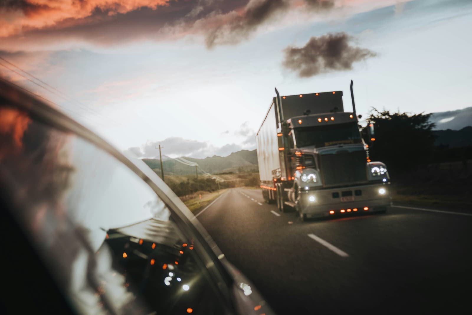 Semi-truck with trailer driving on a highway at dusk